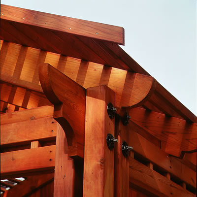 Corner of a pergola with shaped redwood beams and timbers.